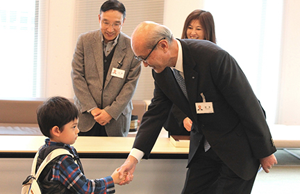 宮本会長と握手を交わす男児。初めての名刺交換の後で、少し緊張した様子
