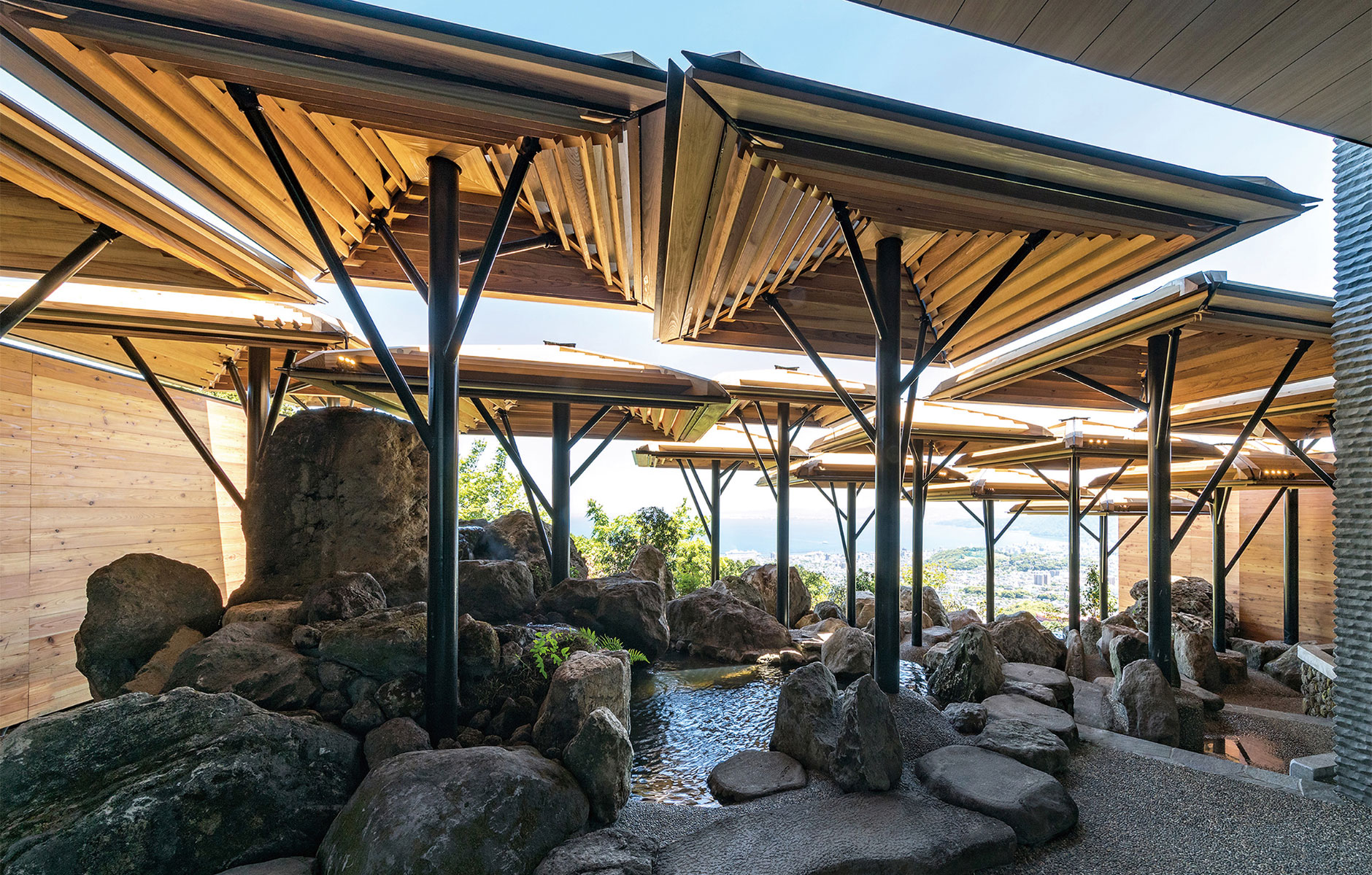 The outdoor bath on the first floor with its impressive massive Beppu stone boulders and umbrellas made of cedar louvers.