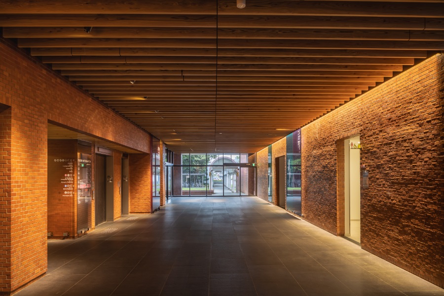 Main building entrance. The wall bricks and floor tiles were reused, and the wall surfaces were showcased with lighting. Fire-resistant lumber developed by AIST was used liberally in the ceiling.