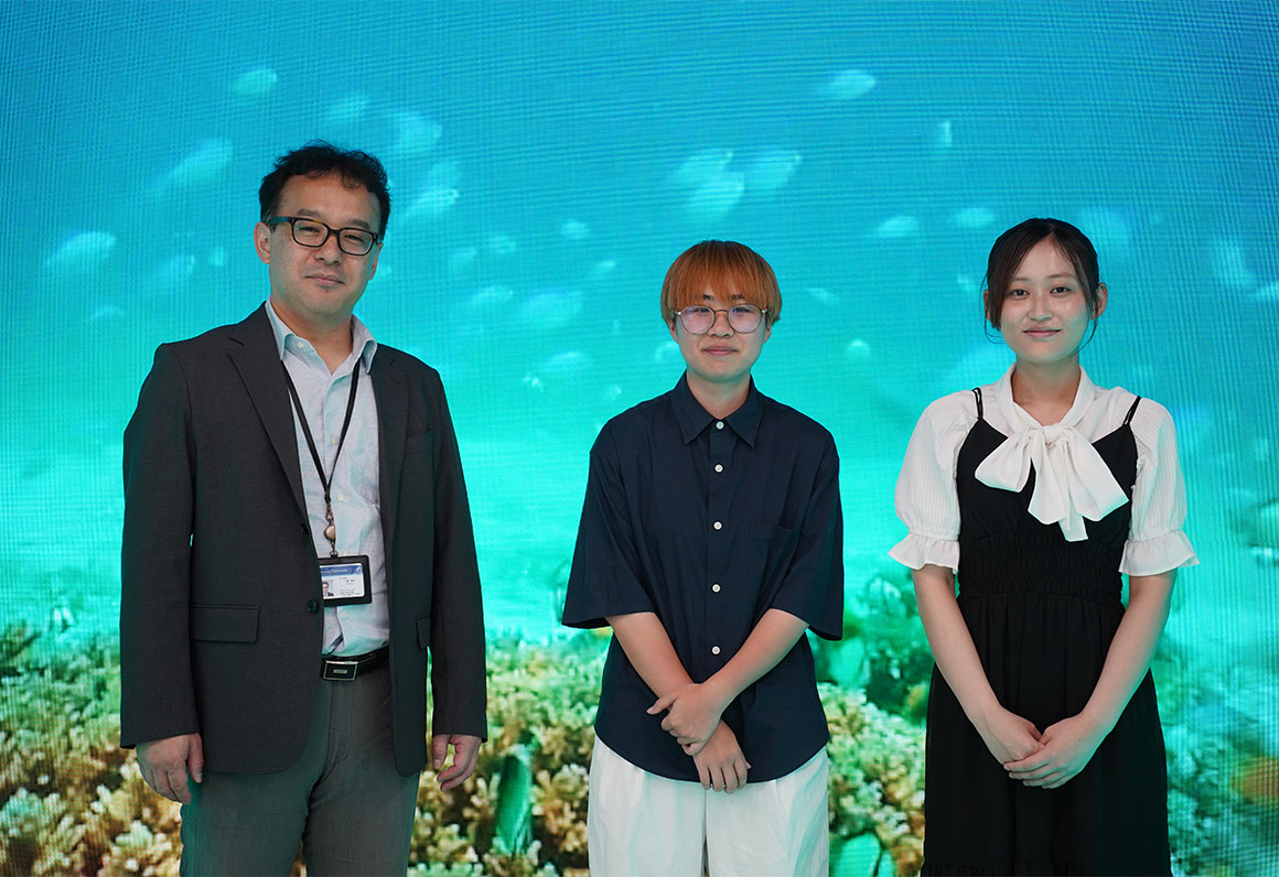 松山大学 情報学部 学部長 檀 裕也 様（写真左）、情報学部 濱松 麻里亜さん（写真中央）、梶原 瑠菜さん（写真右）