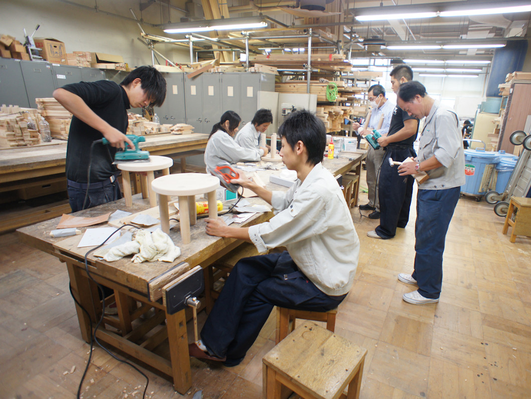 椅子の製作では、脚は木工旋盤（木材を回転させて、固定した刃で切削する工作機械）を使用して曲線に加工したり、座面と脚の接合は、ボール盤（穴を開けるための工作機械）を使っての丸穴の加工や、クリアー塗装（材料の素地が透けて見える無色透明の塗装）までを生徒の手で行いました