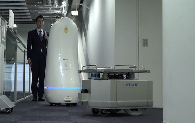 6階の廊下では、来館者を伴った案内ロボットと物流用ロボットが鉢合わせるが、案内ロボットが一時停止し来館者に注意を促すことで安全にすれ違うことができた。